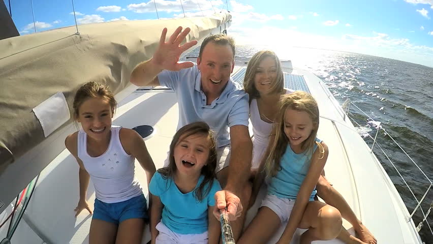 Familie mit drei Kinder sitzt auf einem Boot und macht ein Selfie
