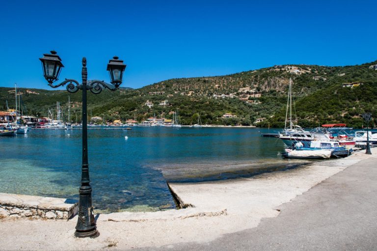 Die Hafenpromenade von Syvota: Boote, die vor Anker liegen, blaues Wasser und grüne Hügel.