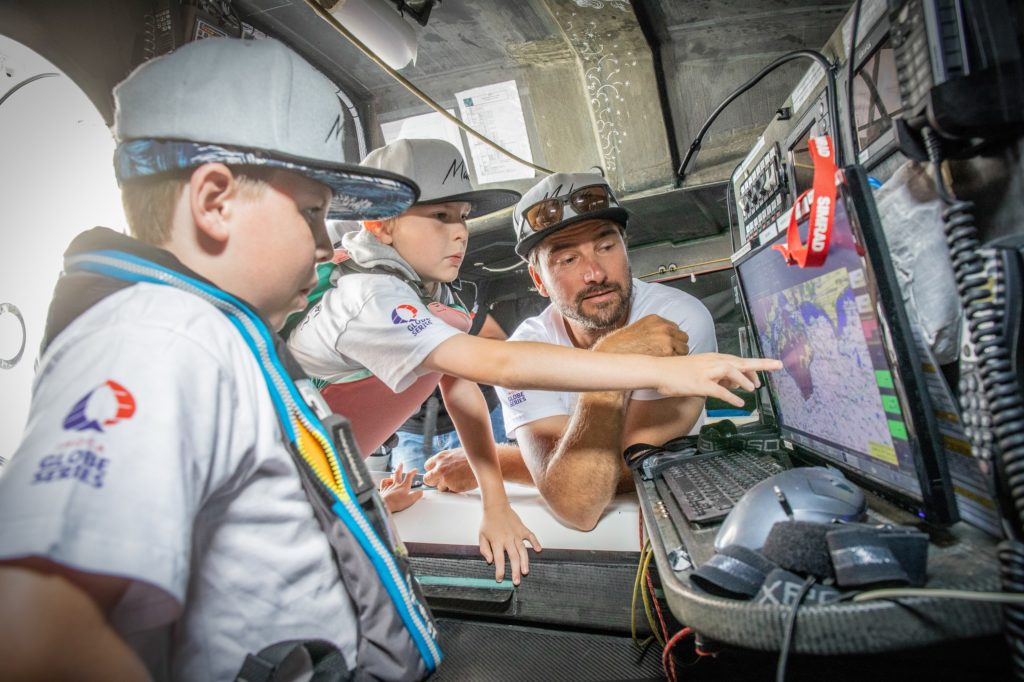 Boris Herrmann unterrichtet zwei Schulkinder im Inneren eines Hochseesegelboots