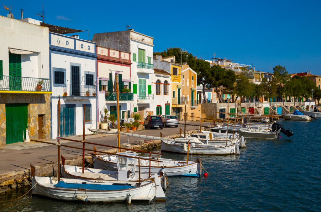 Authentisch-bunte Fischerhäuser und dazugehörige traditionelle Segelboote auf Ihrem Bootsausflug von Cala D'Or nach Porto Cristo 