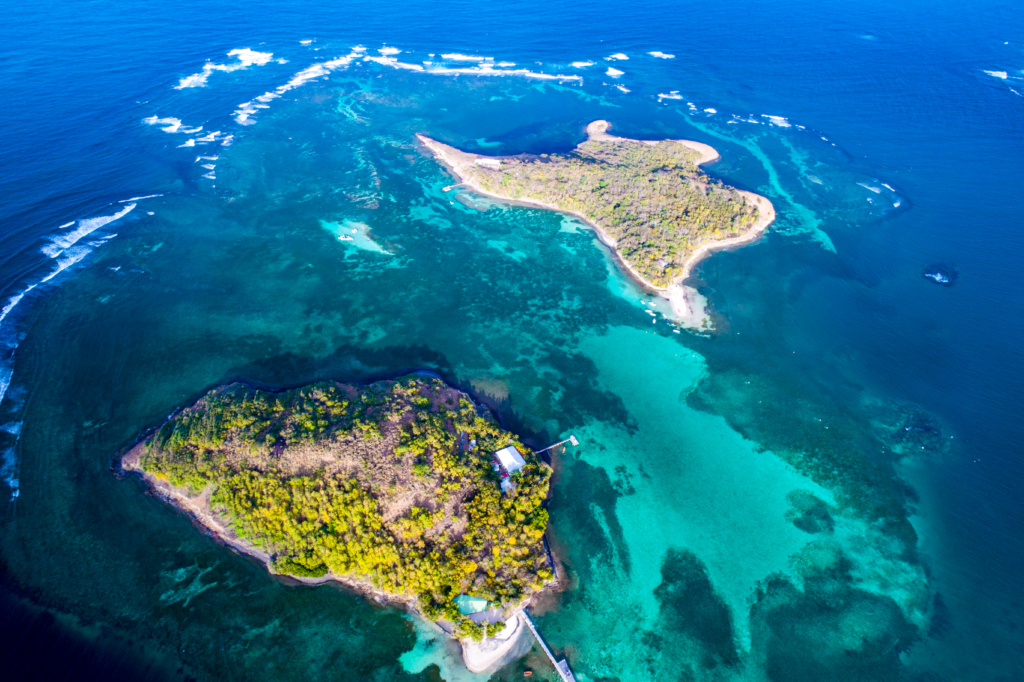Josephines Badewanne und die Insel Oscar von oben. Türkisblaues Wasser mit durch das Wasser scheinenden Korallen umranden die kleine Insel Oscar.