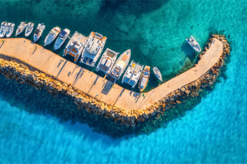 Vista aerea di barche a motore e catamarani ormeggiati in una marina dalle acque turchesi